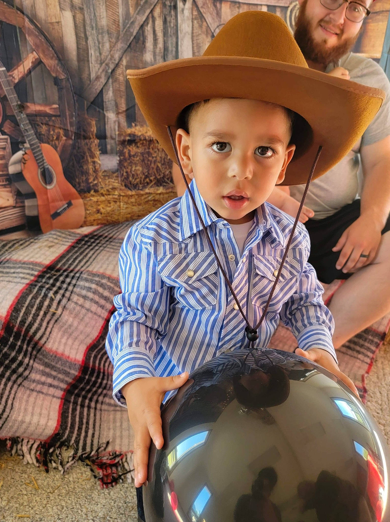 Marcell is registered to the contest to win money with this photo: child, cowboy_hat, fashion_accessory, fedora, fun, guitar, happy, hat, headwear, leisure, musical_instrument, pattern, person, recreation, sitting, sun_hat, sunglasses, t_shirt, toddler, vacation