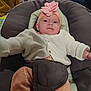 baby, infant, headband, pink_flower, clothing, baby_seat, cushion, wooden_chair, indoor, person, cute, reclining, cozy, home, furniture, child, portrait, soft_toys, curious, comfortable