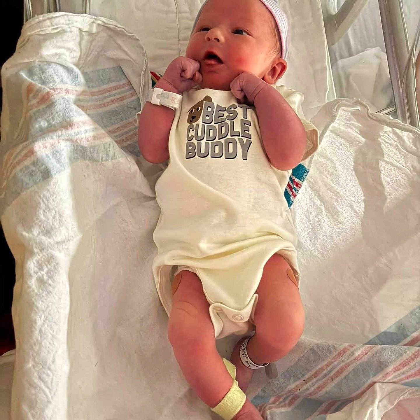 Eli is registered to the contest to win money with this photo: newborn, baby, infant, child, hospital, bassinet, blanket, swaddle, onesie, hat, wristband, pacifier, portrait, lying_down, sleeping_area, face, hands, feet, striped_blanket, cuddly