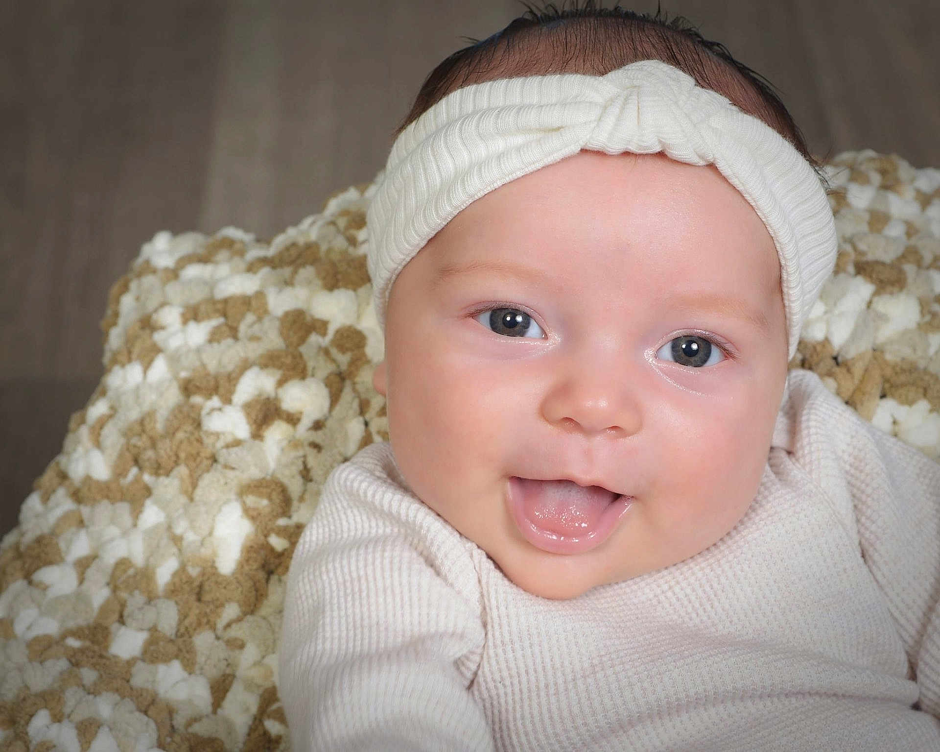 Lily joined the competition — help win amazing prizes! baby, infant, face, headband, tongue_out, blue_eyes, blanket, close_up, smiling, cute, child, soft_texture, white_clothing, happy, portrait, indoor, skin, newborn, person, expression