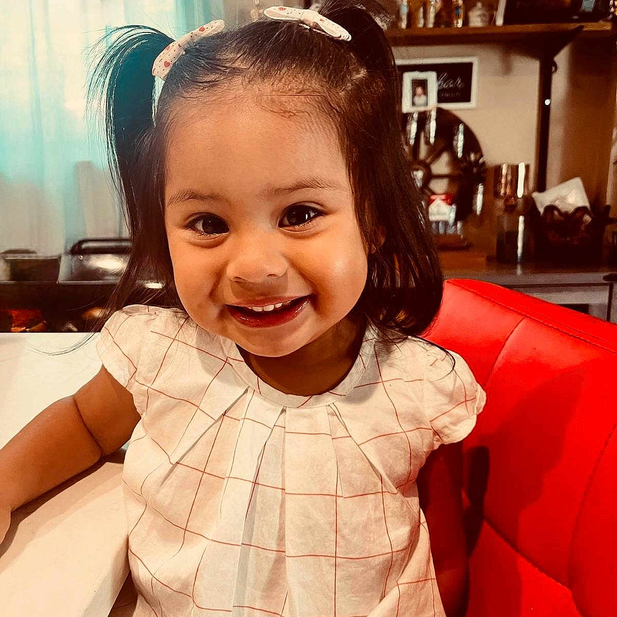 Ariana Michelle is registered to the contest to win money with this photo: cheerful, child, clothing, cute, decor, dressed, face, furniture, girl, hair_clips, happy, home, indoor, person, pigtails, portrait, red_chair, smile, white_table, young_child