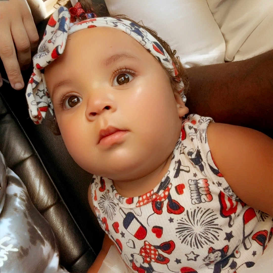 Neyehmoni is registered to the contest to win money with this photo: baby, big_eyes, child, closeup, colorful_clothing, curious, cute, expression, face, hand, headband, indoor, infant, light, patterned_outfit, person, seated, skin, soft_texture, tutu_skirt