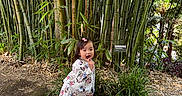 Shakira joined the competition — help win amazing prizes! child, toddler, girl, outdoor, bamboo, garden, botanical_garden, plants, nature, greenery, tropical, path, standing, walking, smiling, surprised, open_mouth, patterned_clothing, sneakers, portrait