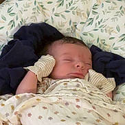 Remington joined the competition — help win amazing prizes! baby, newborn, sleeping, blanket, mittens, cushion, floral_pattern, striped, face, infant, cozy, resting, indoors, soft_lighting, peaceful, child, person, fabric, water_bottle, bedroom
