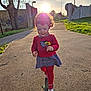toddler, child, flower, dandelion, red_clothing, headband, curly_hair, walking, sunlight, outdoor, pathway, tree, grass, sidewalk, smiling, happy, daylight, nature, person, casual