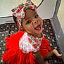 baby, child, tutu, headband, bow, smile, happy, playpen, patterned_clothing, red, infant, cute, sitting, indoors, young_child, joyful, face, person, bright_colors, play