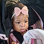 baby, child, car_seat, blanket, pink_bow, headband, infant, cute, portrait, indoors, seatbelt, clothing, hand, face, young_child, black_hair, expression, looking, person, toddler