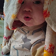 Liam is registered to the contest to win money with this photo: baby, child, blanket, cozy, dinosaur, pajamas, face, cute, indoor, expression, pucker, clothing, soft, colorful, portrait, sitting, infant, warm, head_covering, toddler