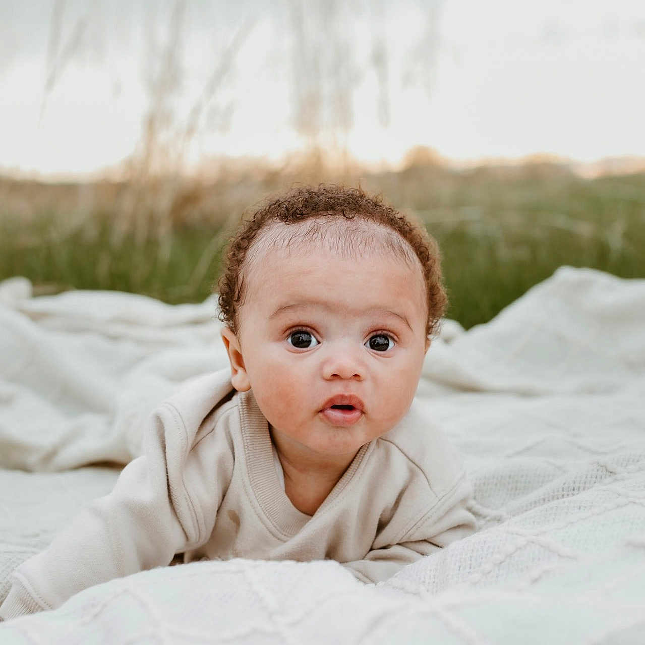Koa joined the competition — help win amazing prizes! baby, blanket, child, clothing, curious, curly_hair, cute, daylight, expression, face, grass, infant, innocence, lying_down, nature, outdoor, portrait, soft_texture, wide_eyes, young_child