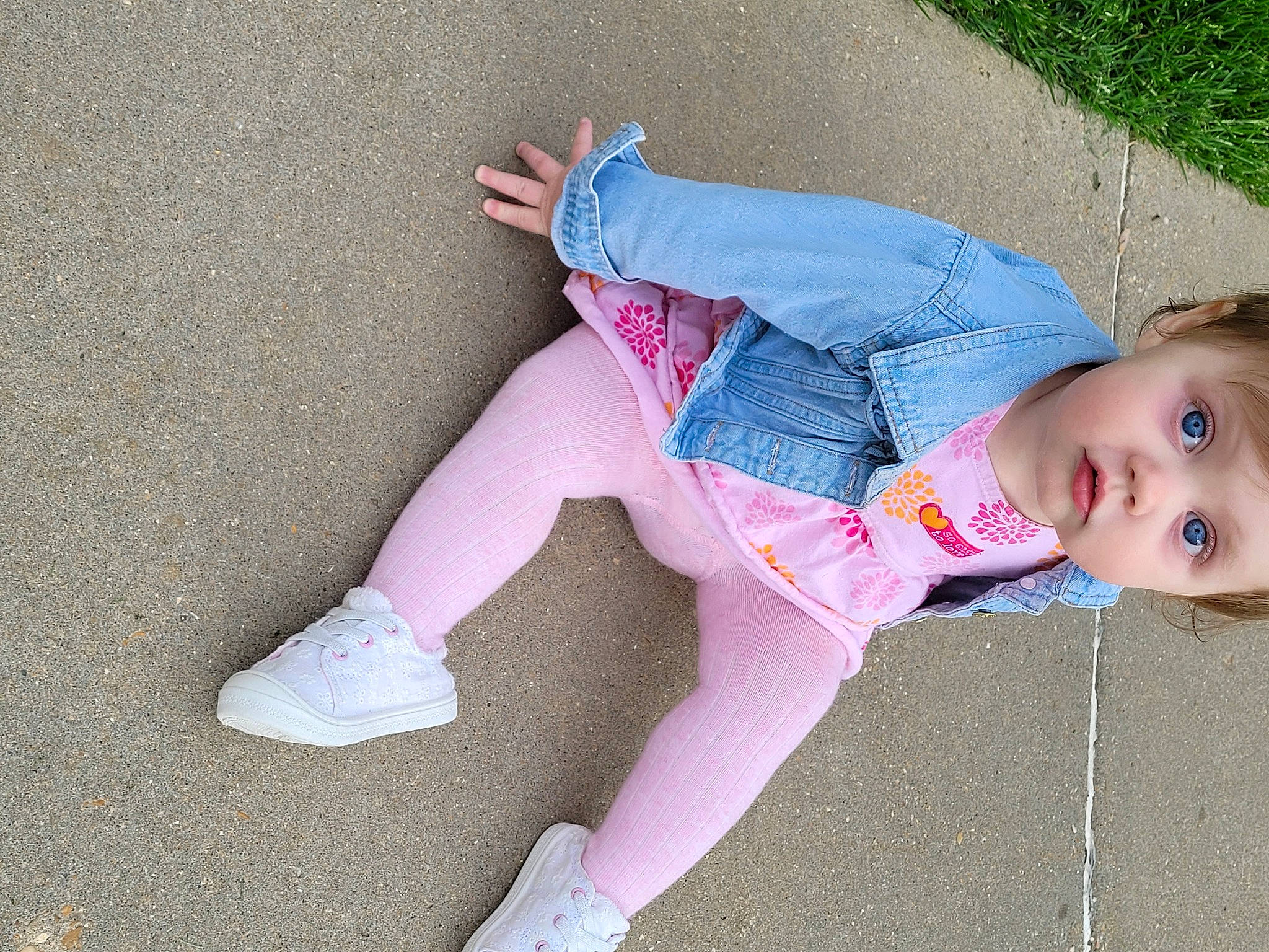 Myla is registered to the contest to win money with this photo: arm, baby_toddler_clothing, child, foot, grass, human_body, human_leg, joint, knee, leg, magenta, pattern, person, pink, plant, shoe, sitting, sneakers, sock, thigh