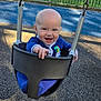 Hudson joined the competition — help win amazing prizes! baby, child, swing, playground, smiling, happy, outdoor, fence, trees, daylight, blue_clothing, infant, reaching_hand, seat, play, park, sunny, ground, person, fun