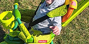 Hudson is registered to the contest to win money with this photo: toddler, child, baby, hoodie, smiling, tricycle, toy, outdoor, grass, sunny, green, canopy, seatbelt, handlebars, footrest, wheel, playtime, happy, dinosaur_pattern, fisher_price