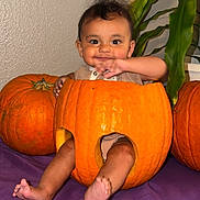 Julian joined the competition — help win amazing prizes! baby, pumpkin, child, orange, smile, plant, indoor, cute, legs, face, purple_cloth, wall, sitting, happy, holiday, decoration, seasonal, cute_expression, festive, fun