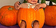 Julian joined the competition — help win amazing prizes! baby, pumpkin, hollowed_pumpkin, child, smiling, legs, feet, plants, greenery, purple_cloth, indoor, cute, festive, halloween, orange, face, sitting, cozy, carved_pumpkin, happy