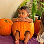 baby, pumpkin, carved_pumpkin, legs, sitting, cute, child, orange, plant, indoor, purple_cloth, decor, face, expression, autumn, holiday, fun, portrait, toes, wall