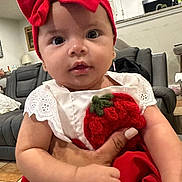 Aislin is registered to the contest to win money with this photo: baby, child, red_bow, headband, dress, indoor, living_room, person, cute, infant, hand, watch, couch, furniture, white_wall, curious, closeup, adorable, portrait, holding