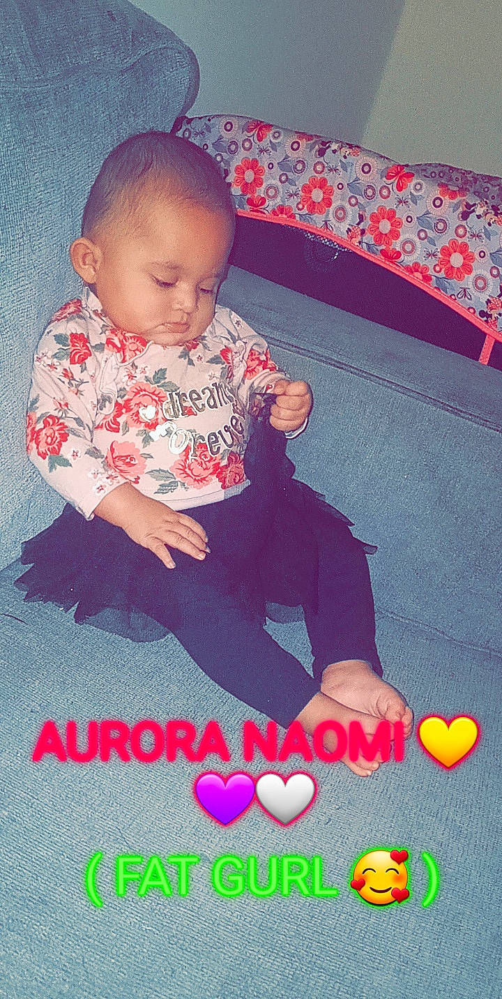 Aurora is registered to the contest to win money with this photo: baby, baby_toddler_clothing, black, child, comfort, couch, event, face, finger, fun, happy, lap, magenta, pattern, person, pink, red, sleeve, t_shirt, textile