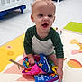 baby, bright, child, clothing, colorful, crib, cute, early_childhood, floor, happy, indoor, person, playmat, playroom, sitting, smiling, soft_book, toddler, toy, young_child