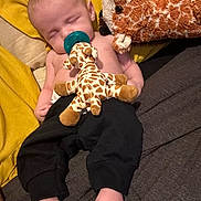 Koah is registered to the contest to win money with this photo: baby, black_pants, blanket, child, comfort, cozy, cute, feet, giraffe, indoors, infant, nap, pacifier, person, relaxing, sleeping, soft_toy, stuffed_animal, toy, yellow