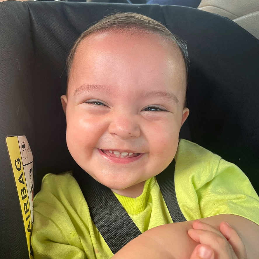 Aiden is registered to the contest to win money with this photo: accessories, baby, belt, bodypart, cushion, face, finger, hand, happy, head, homedecor, laughing, mouth, person, photography, portrait, smile, transportation, vehicle, wrist