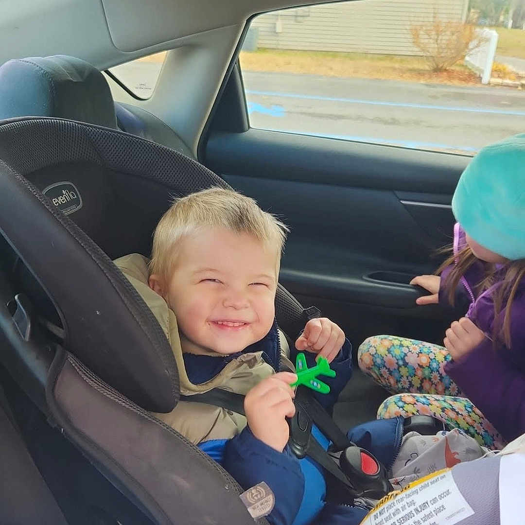 Bentley is registered to the contest to win money with this photo: architecture, baby, building, car, car_interior, carseat, clothing, coat, cushion, face, head, homedecor, jacket, outdoors, person, photography, portrait, shelter, transportation, vehicle