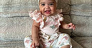 Kaylanna is registered to the contest to win money with this photo: baby, child, clothing, comfortable, couch, cute, face, furniture, happy, headband, home, indoors, infant, person, portrait, sitting, skin, smiling, textile, young