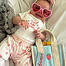 Kaylanna is registered to the contest to win money with this photo: accessory, baby, bow_headband, child, cute, fashion, happy, heart_shaped_sunglasses, indoor, infant, onesie, pants, pink_sunglasses, playful, portrait, smiling, soft_blanket, strawberry_pattern, tote_bag, white_background