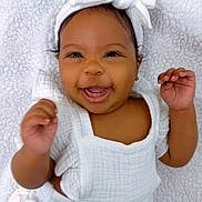 Camilla is registered to the contest to win money with this photo: baby, smiling, white_clothing, headband, bow, infant, happy, lying_down, blanket, soft_texture, cute, portrait, child, newborn, hands_up, indoors, closeup, face, skin, person