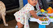Ailani is registered to the contest to win money with this photo: activity_table, baby, child, colorful, curious, dog, door, dress, earrings, floor, furniture, indoor, person, pink_bow, play, porch, sneakers, toddler, toy, wooden_floor