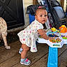 activity_table, baby, child, colorful, curious, dog, door, dress, earrings, floor, furniture, indoor, person, pink_bow, play, porch, sneakers, toddler, toy, wooden_floor