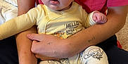 Sawyer is registered to the contest to win money with this photo: baby, child, infant, person, adult, arms, yellow_onesie, cartoon_characters, red_shirt, holding, indoor, bed, blanket, cute, portrait, face, expression, skin, hand, foot