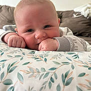 Sawyer is registered to the contest to win money with this photo: baby, infant, face, hand, pillow, floral_pattern, couch, indoor, cute, child, closeup, person, smiling, soft_lighting, cozy, young_child, portrait, comfortable, home, sleeve