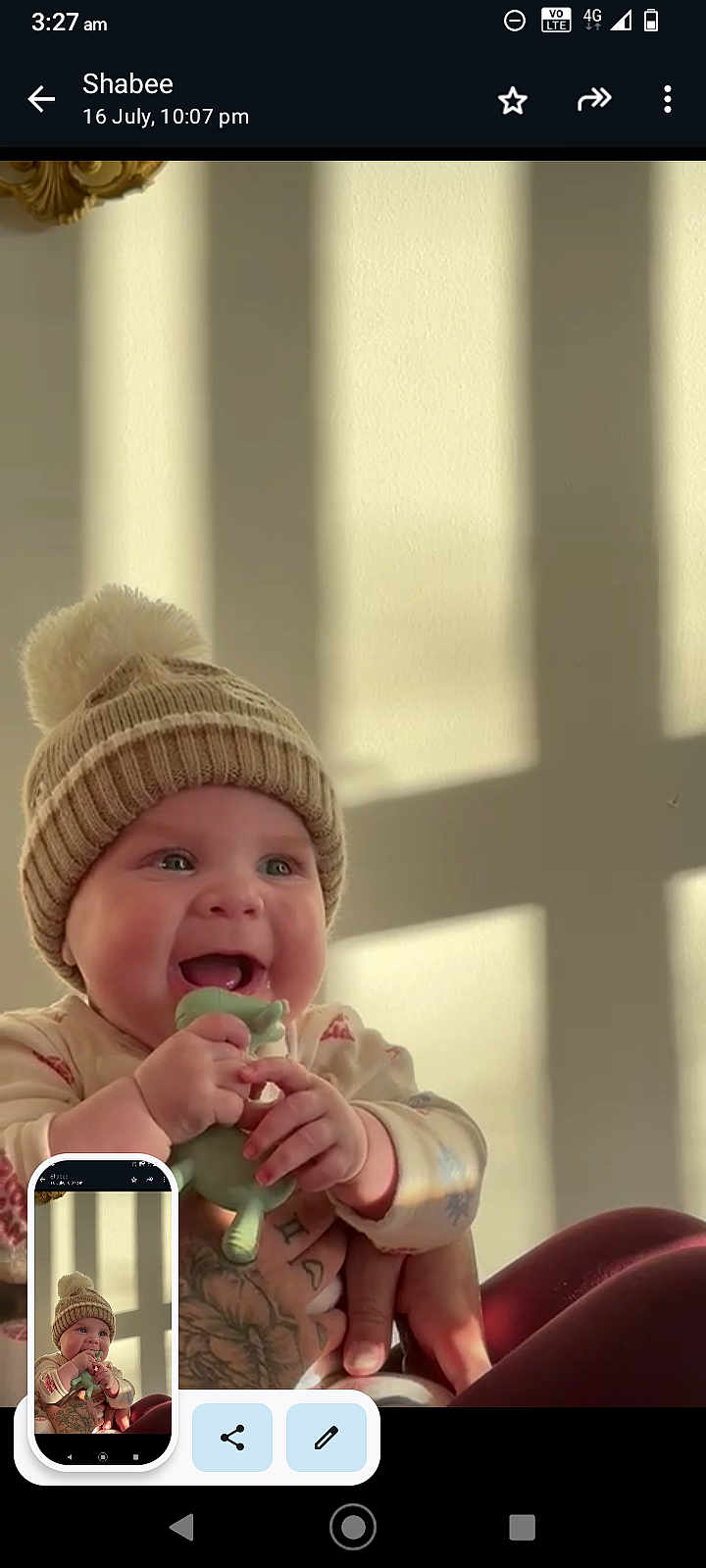 Maxi joined the competition — help win amazing prizes! baby, child, hat, knit_hat, pom_pom, toy, green_toy, hands, tattoos, happy, smiling, indoor, sunlight, shadow, wall, person, infant, cute, cozy, wearing