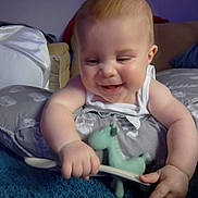 Maxi joined the competition — help win amazing prizes! arm, baby, child, closeup, cushion, cute, face, furniture, giraffe_toy, happy, home, indoor, infant, person, pillow, smiling, soft_lighting, spoon, toy, white_clothing