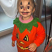 Larya participe au concours pour gagner de l'argent avec cette photo : child, face_paint, pumpkin_costume, halloween, indoors, window, curtain, braids, sneakers, floor, smile, orange_clothing, green_collar, person, festive, holiday, costume, cute, standing, young