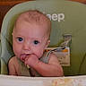 Bradley is registered to the contest to win money with this photo: baby, bib, chewing, child, face, finger, food, green_chair, hand, harness, high_chair, indoor, infant, mealtime, photography, portrait, sitting, tray, wide_eyes, wooden_background