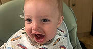 Bradley joined the competition — help win amazing prizes! baby, bib, blond_hair, blue_eyes, cabinets, car_pattern, child, close_up, countertop, family_photo, happy, high_chair, home, indoor, infant, kitchen, open_mouth, portrait, seated, smiling