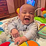 baby, smiling, toy, piano, colorful, pajamas, indoor, wooden_furniture, book, playtime, child, happy, infant, face, hands, floor, door, dresser, plastic_toys, room