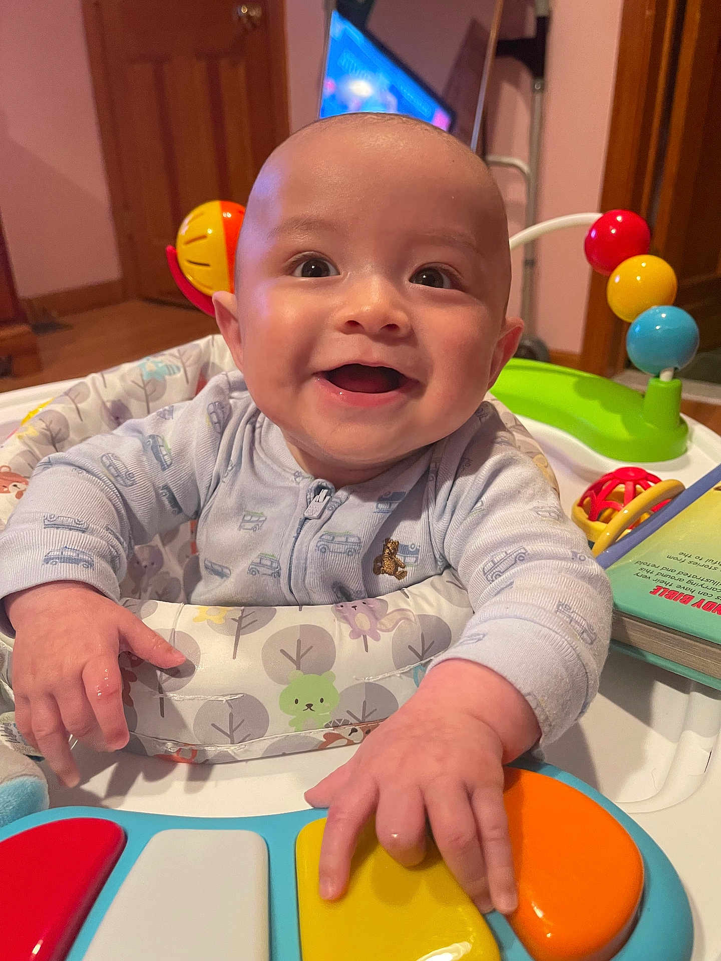Clayton joined the competition — help win amazing prizes! baby, smiling, toy_piano, activity_center, indoor, child, happy, play, hands, colorful, face, clothing, wooden_floor, door, book, furniture, head, expression, toy, person