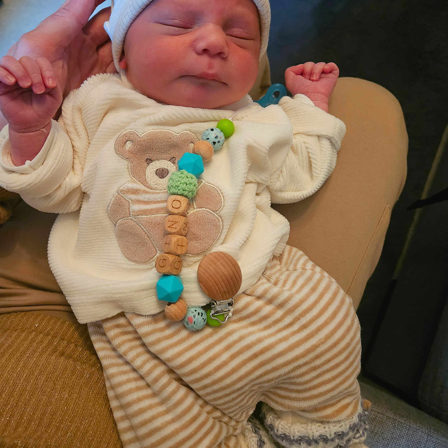 Gino participe au concours pour gagner de l'argent avec cette photo : baby, bear_ears, closeup, clothing, cozy, cute, hand, hat, holding, indoor, infant, knitted_booties, newborn, peaceful, person, sleeping, soft_texture, striped_pants, teddy_bear, warm_colors