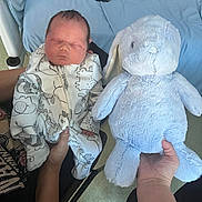 Lennox is registered to the contest to win money with this photo: animal_pattern, baby, bed, blanket, blue_bunny, child, clothing, comfort, cute, hand, indoor, infant, newborn, onesie, person, resting, sleeping, soft_toy, stuffed_toy, toy