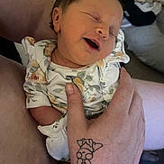 Eleanor is registered to the contest to win money with this photo: newborn, baby, infant, smiling, sleeping, hand, tattoo, floral_clothing, person, indoor, closeup, skin, cute, holding, relaxation, comfort, family, portrait, young_child, human