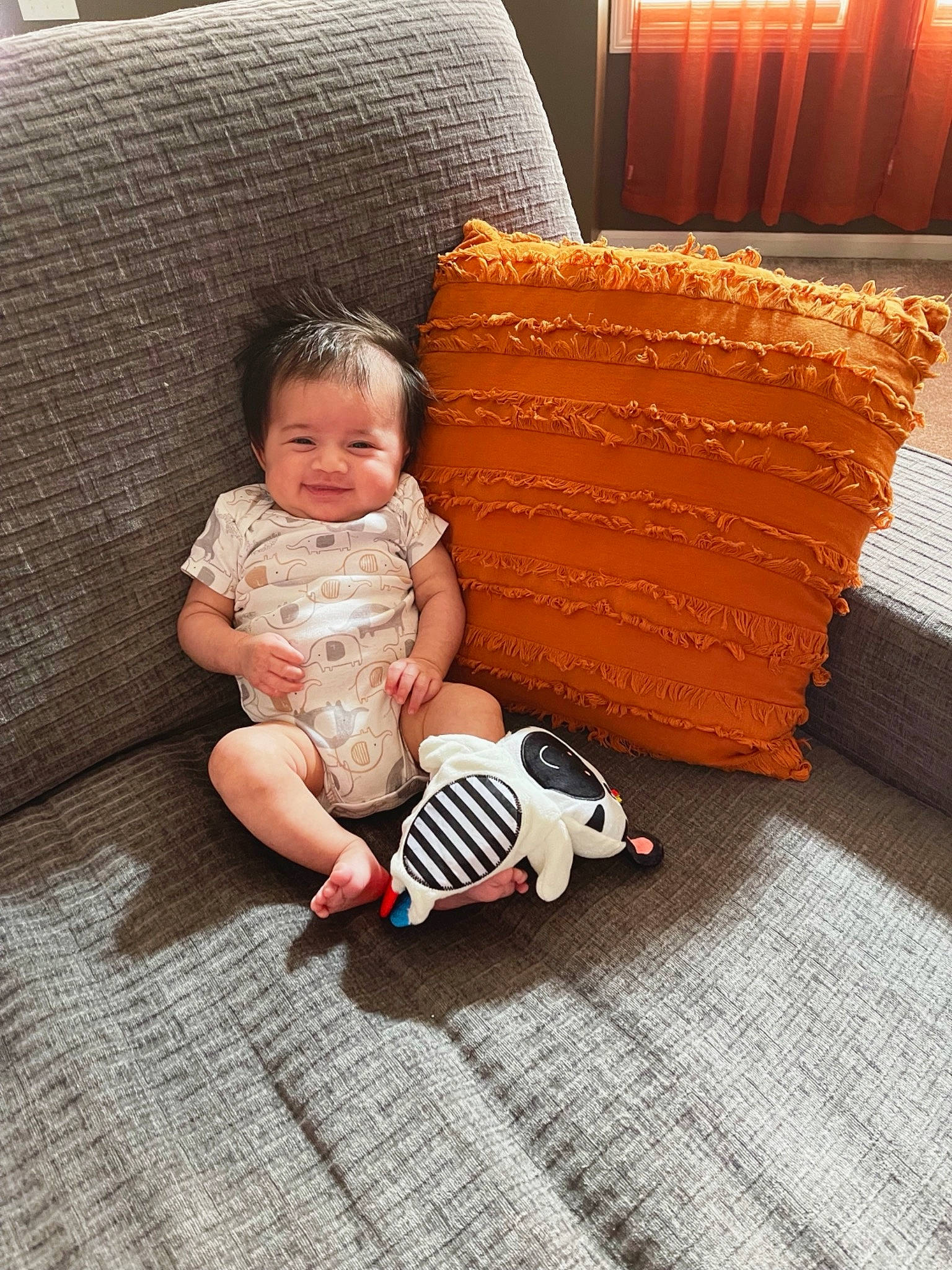 Princeton is registered to the contest to win money with this photo: baby, baby_toddler_clothing, child, comfort, couch, floor, flooring, foot, fun, grass, hardwood, human_leg, joy, pattern, person, room, sitting, sock, thigh, toddler