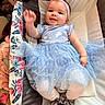 baby, baby_girl, blue_dress, child, comfortable, cute, dress, flower_pattern, happy, headband, indoors, infant, lying_down, person, pink, playpen, shoes, smiling, tights, young_child
