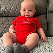 Tucker joined the competition — help win amazing prizes! baby, infant, red_onesie, milk_carton_graphic, gray_socks, quilted_couch, leather_furniture, blanket, blue_eyes, pout, sitting, indoors, cute, child, portrait, soft_lighting, texture, cozy, hand, footwear