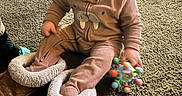 Osiris joined the competition — help win amazing prizes! baby, child, infant, smiling, sitting, indoor, carpet, slippers, oversized_shoes, fuzzy, pink_outfit, toy, colorful_toy, dog, cushion, living_room, portrait, happy, playful, cozy