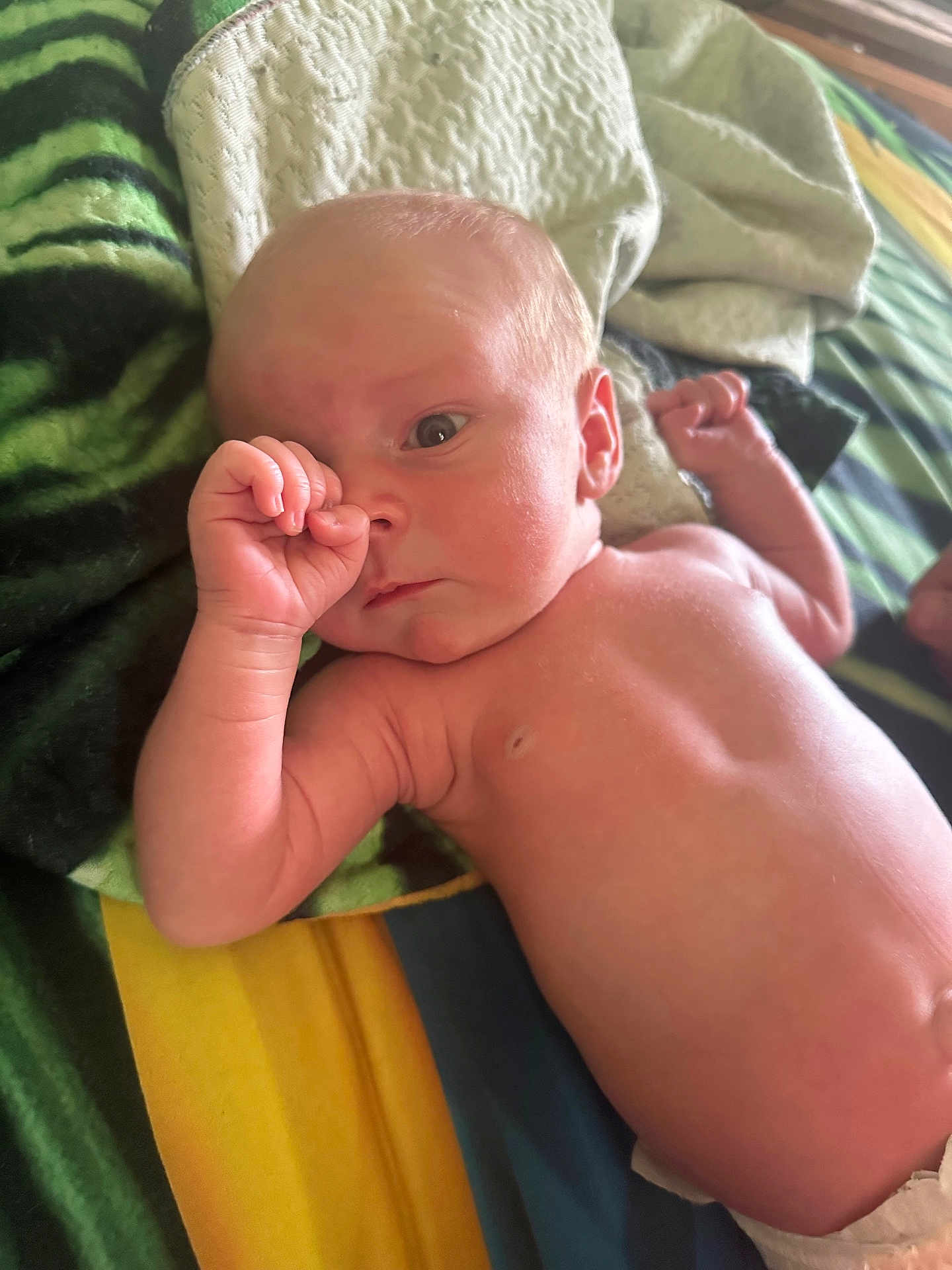 Arlo is registered to the contest to win money with this photo: baby, infant, thumb_sucking, blanket, colorful_blanket, skin, newborn, lying_down, bed, soft_texture, curious_expression, human, child, portrait, indoors, diaper, small_hand, head, face, resting