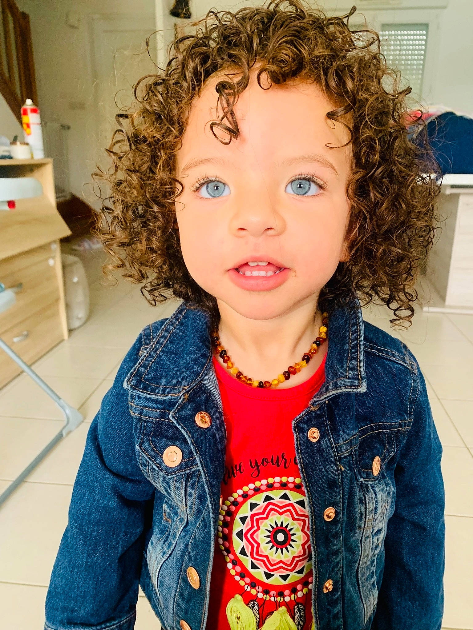Loé participe au concours pour gagner de l'argent avec cette photo : baby_toddler_clothing, cheek, chin, ear, eye, eyebrow, facial_expression, fashion, hair, happy, head, iris, jheri_curl, neck, nose, outerwear, person, ringlet, skin, sleeve