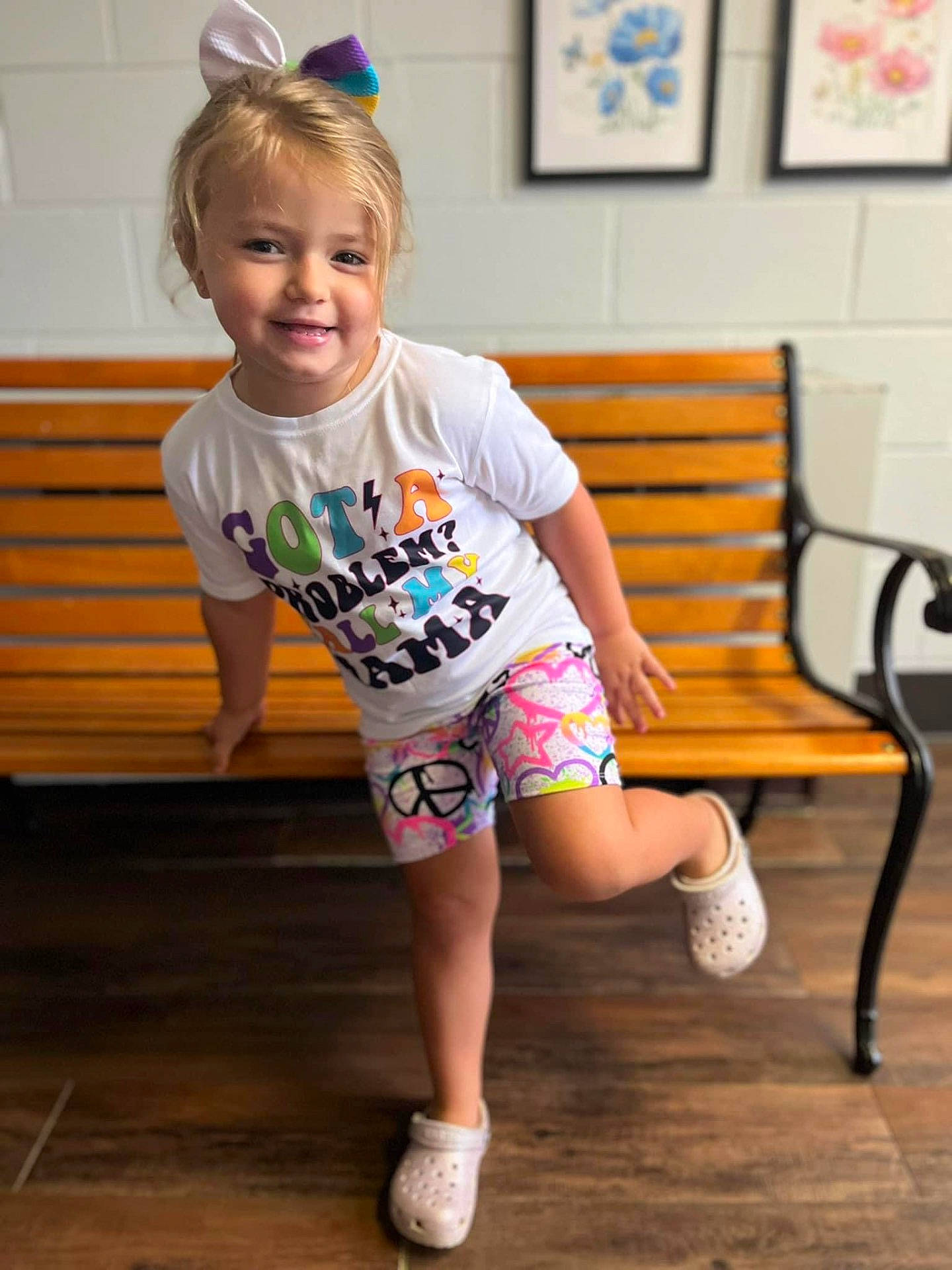 Camilla is registered to the contest to win money with this photo: bench, child, clothing, face, female, footwear, furniture, girl, hardwood, head, person, photography, portrait, shoe, shorts, sitting, sleeve, sneaker, t_shirt, wood