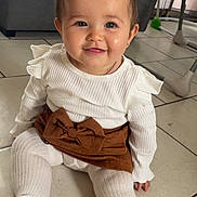 Nilya participe au concours pour gagner de l'argent avec cette photo : baby, child, smiling, indoor, floor, white_clothing, brown_skirt, hair_bow, tights, cute, sitting, portrait, happy, person, infant, tiled_floor, fashion, accessory, young_child, headwear